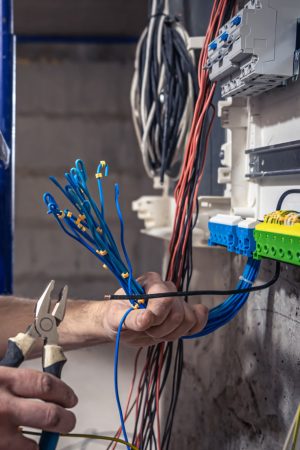 male-electrician-works-switchboard-with-electrical-connecting-cable